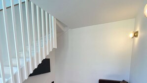 Un salon moderne avec un canapé d’angle, une petite table ronde et un escalier doté de rampes blanches.