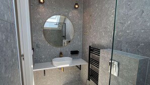 Une salle de bain moderne avec un miroir rond, un lavabo blanc et des toilettes.