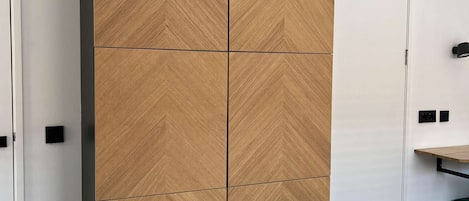 Une chambre dotée d’une grande armoire, d’un lit, d’un bureau et d’un luminaire fixé au mur.