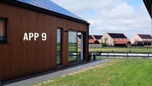Een modern gebouw met een houten gevel en grote ramen, aangeduid met 