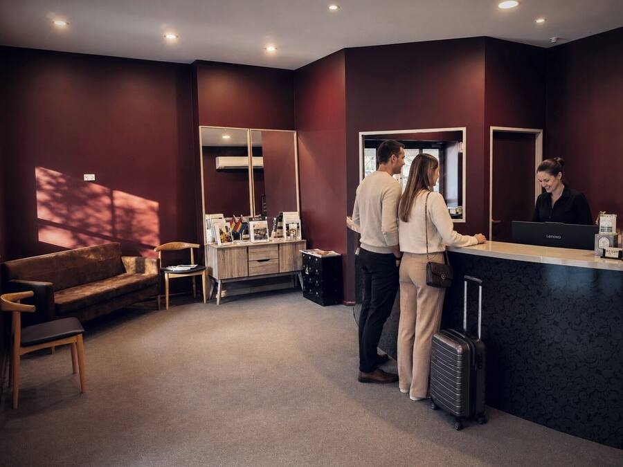 A reception area with a reception desk, a sofa, a chair, and a large mirror.