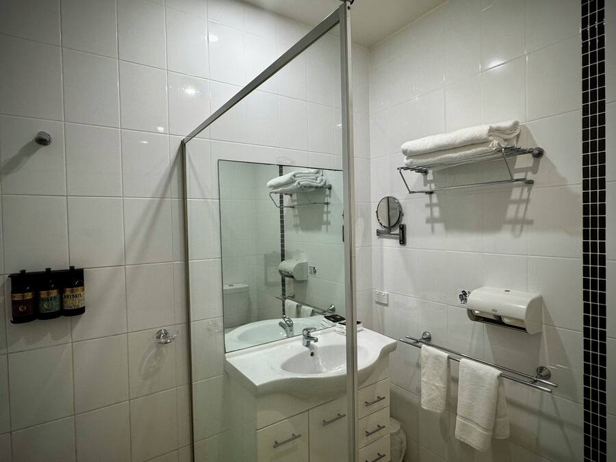 A modern bathroom with a glass shower enclosure, a sink, and a mirror.