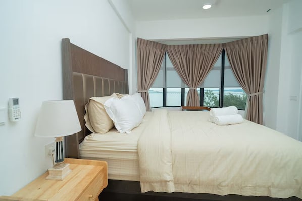 Une chambre d’hôtel avec un lit, une table de chevet avec une lampe et une vue sur l’extérieur grâce à de grandes fenêtres.