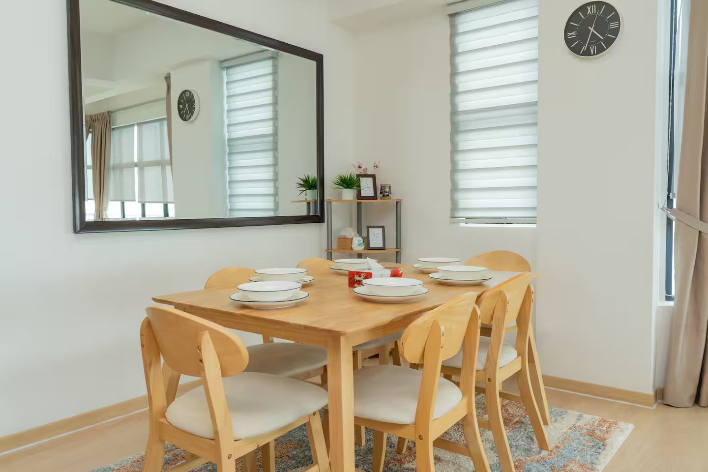 Un comedor con una mesa de madera, seis sillas y un espejo en la pared.