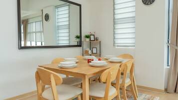 Un comedor con una mesa de madera, seis sillas y un espejo en la pared.