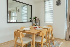 Un coin repas avec une table en bois, six chaises et un miroir au mur.