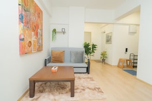 Un salon avec un canapé, une table basse et un tableau accroché au mur.