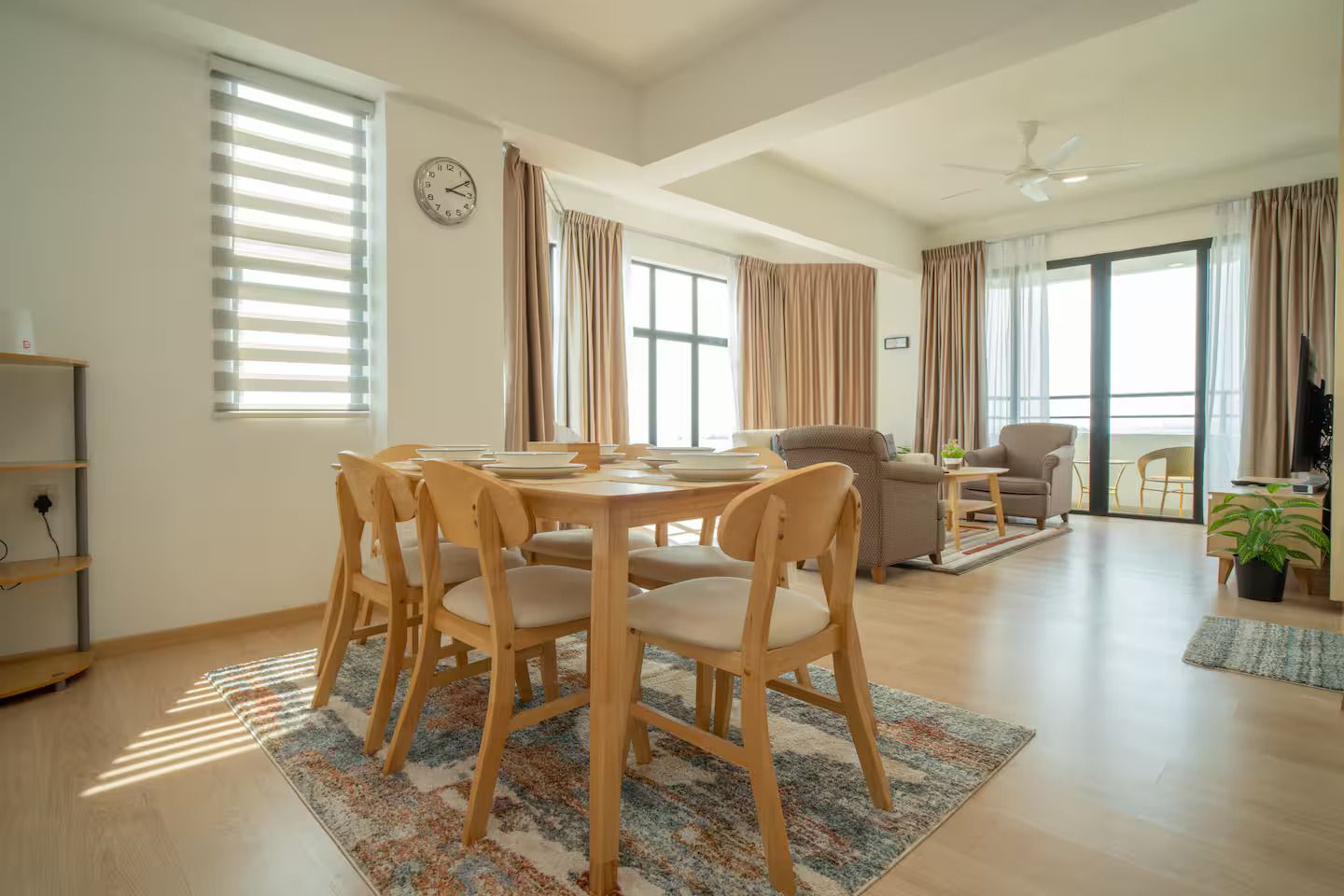 Un vaste espace de vie comprenant une table à manger, des chaises, un canapé et un ventilateur de plafond.
