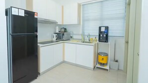 Uma cozinha compacta com geladeira preta, micro-ondas, cafeteira e pia.