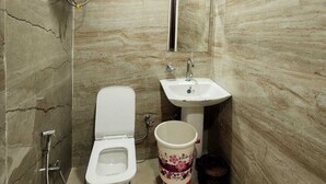 Une petite salle de bain comprenant des toilettes, un lavabo et un chauffe-eau fixé au mur.