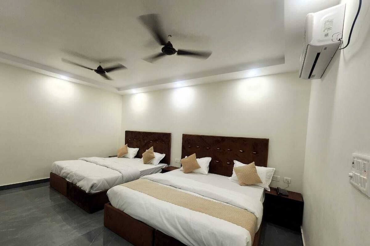 A hotel room with two beds, a ceiling fan, an air conditioning unit, and a bedside table with a phone.