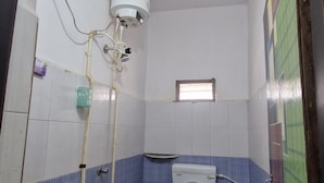 Casa de banho pequena e simples, com sanita, lavatório e um balde.