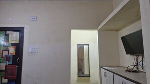 Quarto com porta, espelho, televisão fixada na parede e armário.