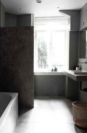 Un baño moderno con bañera, una ventana y un lavamanos.