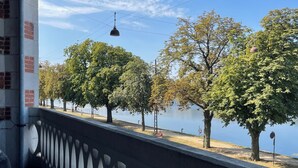 En bro med ett mönstrat räcke som vetter ut över en vattenyta och träd.