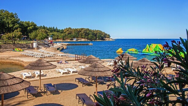 A beach with sun loungers, umbrellas, and a lifeguard tower. - Villa in Vabriga with Pool and Private Garden (Vabriga)