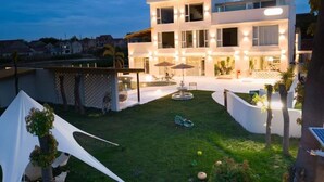 Una casa moderna de dos pisos con un césped cuidado y un espacio exterior para sentarse.