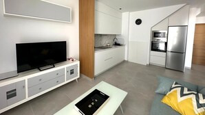 Un soggiorno moderno con una televisione a schermo piatto, un tavolino da caffè e un divano con cuscini.