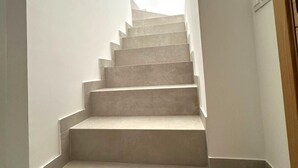 Una scala con tappeto chiaro e pareti bianche.