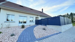 A modern house with a tiled roof, a paved driveway, and a decorative fence.