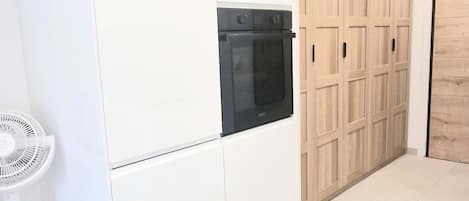 Uma cozinha moderna com forno embutido, armários brancos e uma porta de madeira.