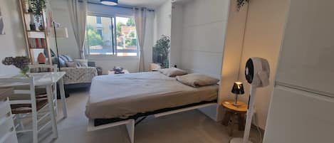 Un dormitorio moderno con cama, mesita de noche, lámpara y ventilador.