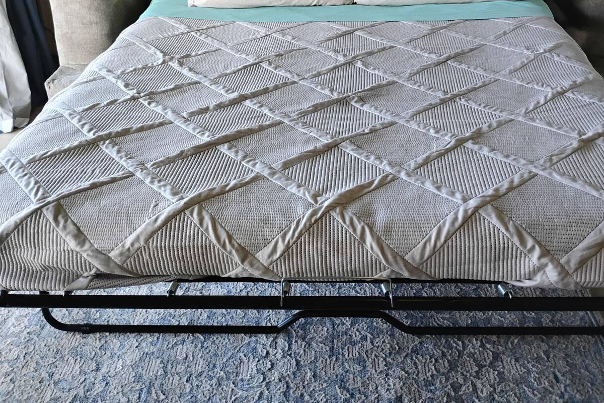 Uma cama com colchão acolchoado, duas almofadas e um cobreleite verde-água.