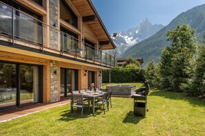 Une maison moderne dotée d’un balcon, d’un coin repas avec mobilier d’extérieur et offrant une vue sur les montagnes.