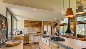 A modern kitchen with wooden cabinetry, a large island, and a view of the outdoors.