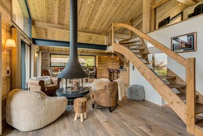 A spacious living area with a large fireplace, wooden furniture, and a wooden staircase.