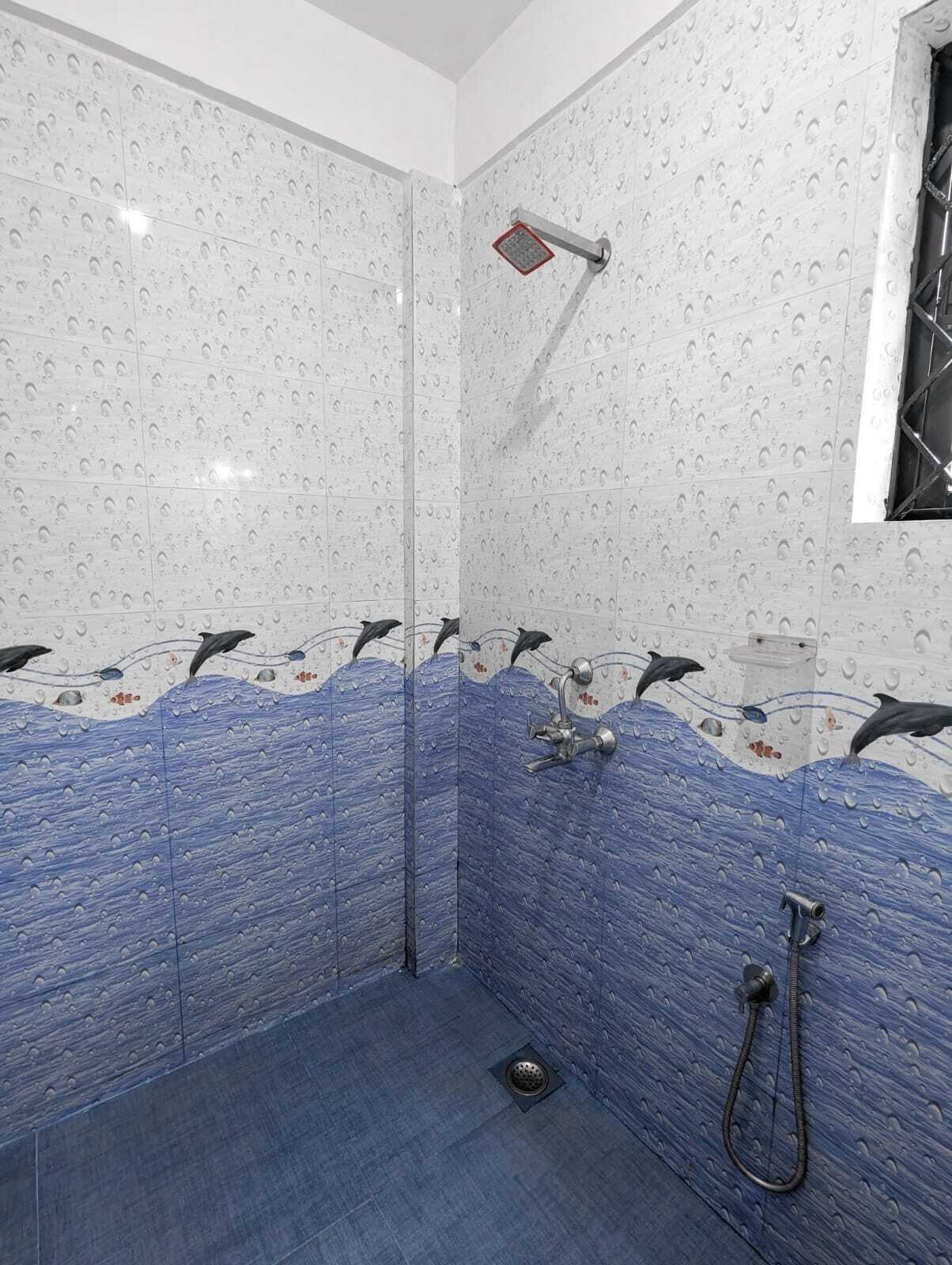 A shower with a dolphin mural on the wall, a handheld showerhead, and a rain showerhead.