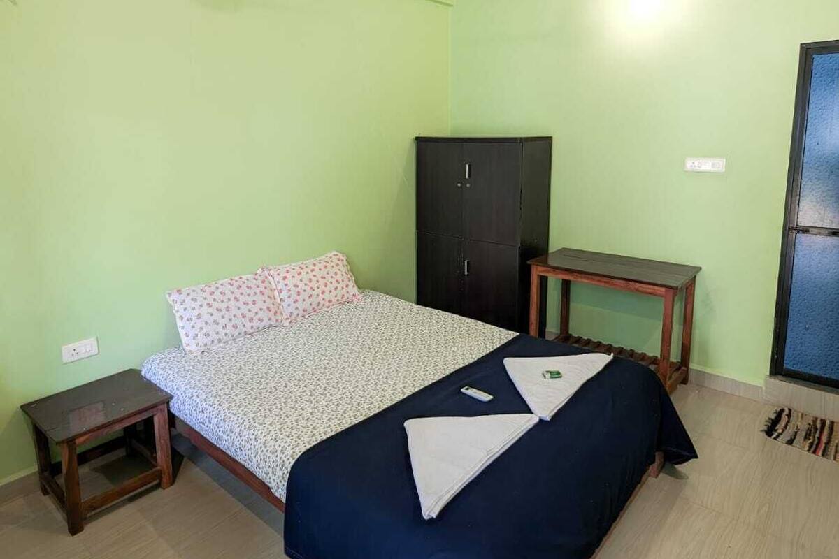 Une chambre à coucher comprenant un lit, une armoire, une petite table et un ventilateur de plafond.