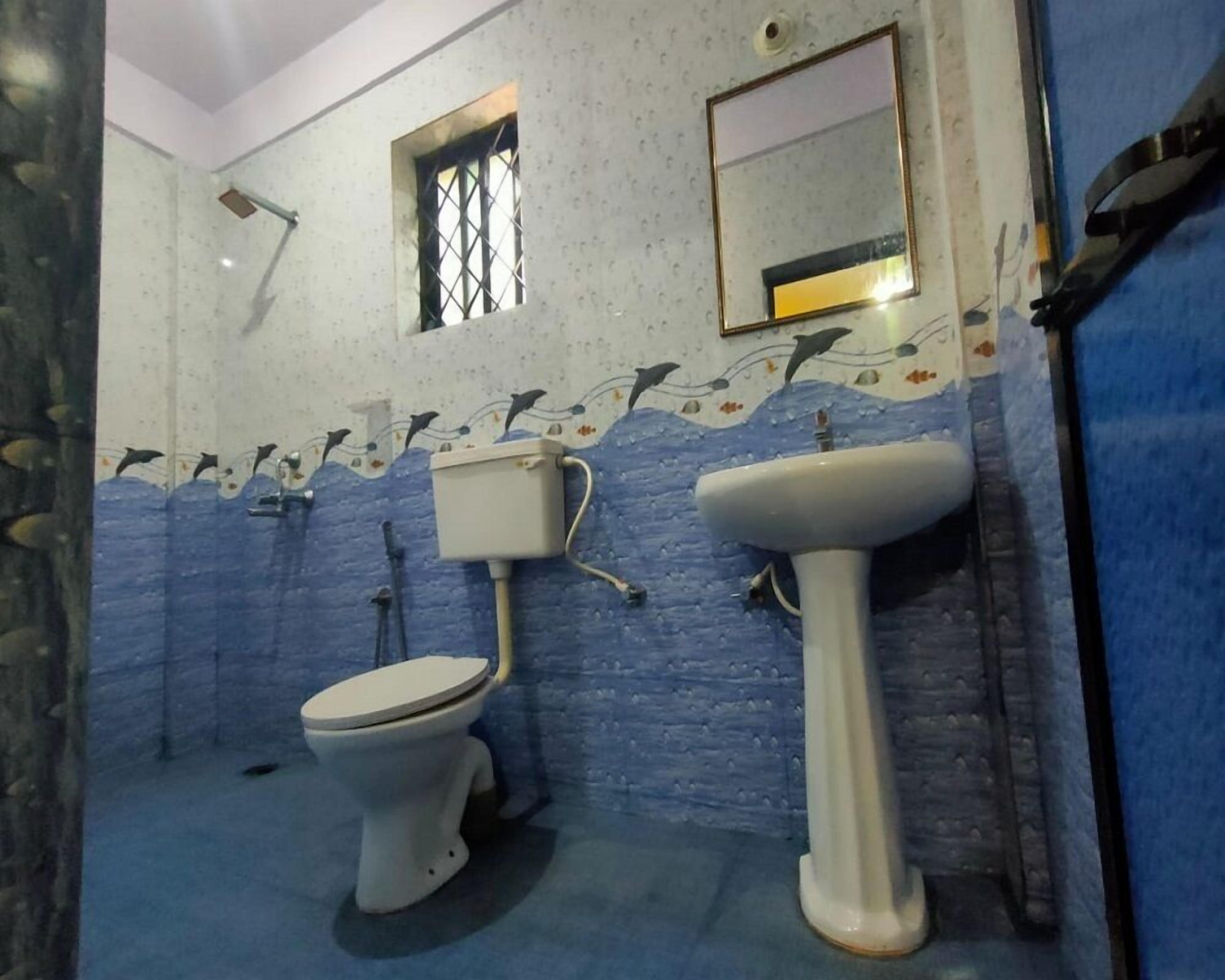 A bathroom with a toilet, a sink, a window, and a mirror.