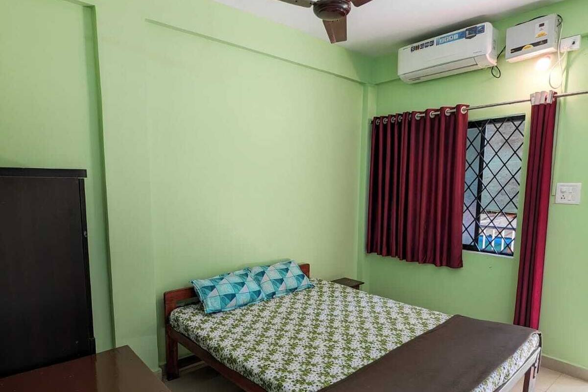Une chambre avec deux lits, un ventilateur de plafond, un appareil de climatisation et une fenêtre avec des rideaux.