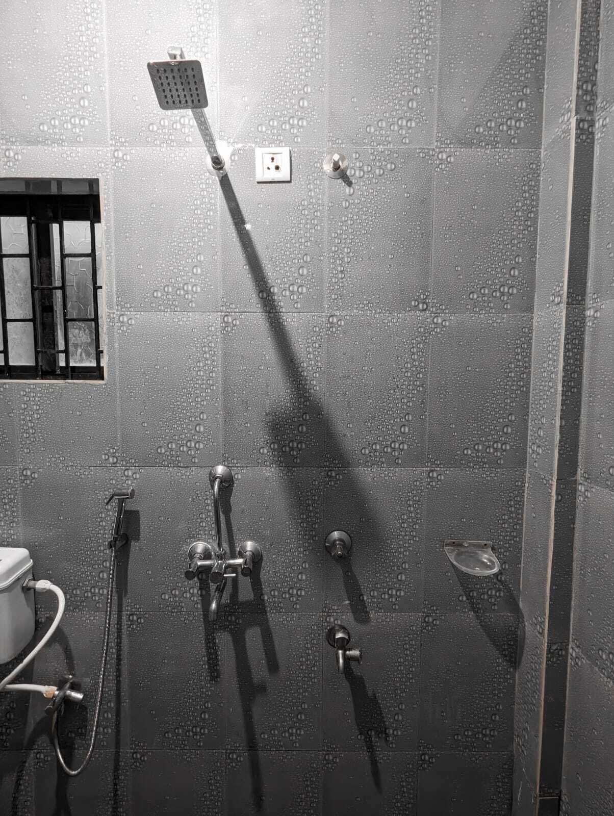Un espace douche moderne doté d’un pommeau de douche à main, d’un pommeau de douche fixé au mur et d’un robinet à main.
