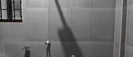 Un espace douche moderne doté d’un pommeau de douche à main, d’un pommeau de douche fixé au mur et d’un robinet à main.