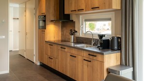A modern kitchen with wooden cabinets, a stainless steel sink, and a window with a view.