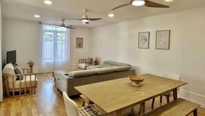 A spacious living area with a wooden dining table, a sofa, and a ceiling fan. - *VILLA SOUS LES PALMES* - 170 m from the lagoon (Saint-Paul)