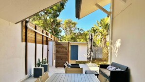A covered patio area with a table and chairs, a small seating area, and a wooden fence. - *VILLA SOUS LES PALMES* - 170 m from the lagoon (Saint-Paul)