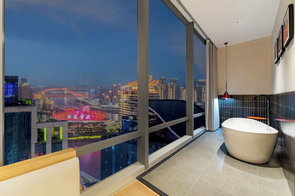 Ein modernes Badezimmer mit einer großen Badewanne, Blick auf die Stadt durch raumhohe Fenster und einem zeitgemäßen Design.