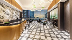 A modern hotel lobby with a marble reception desk, seating area, and large windows offering city views. - Chongqing Haoting Riverside Hotel (Chongqing)