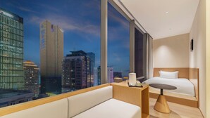 A modern hotel room with a large window offering a city view, a bed, a bedside table, and a sofa. - Chongqing Haoting Riverside Hotel (Chongqing)