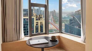 A room with a large window offering a cityscape view, a laptop on a table, and a cup. - Chongqing Haoting Riverside Hotel (Chongqing)