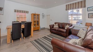 A spacious living area with a brown leather sofa, a wooden dining table with chairs, and a cabinet. - Luxury Apartment, City Break, 4B City Cottage Central Chester (Chester)