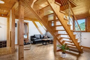 Een houten interieur met een trap, een bank, een tafel en een potplant.