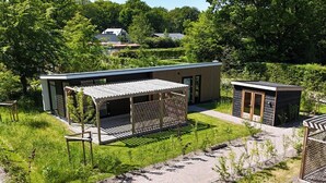 A modern building with a covered outdoor area and a small adjacent structure.