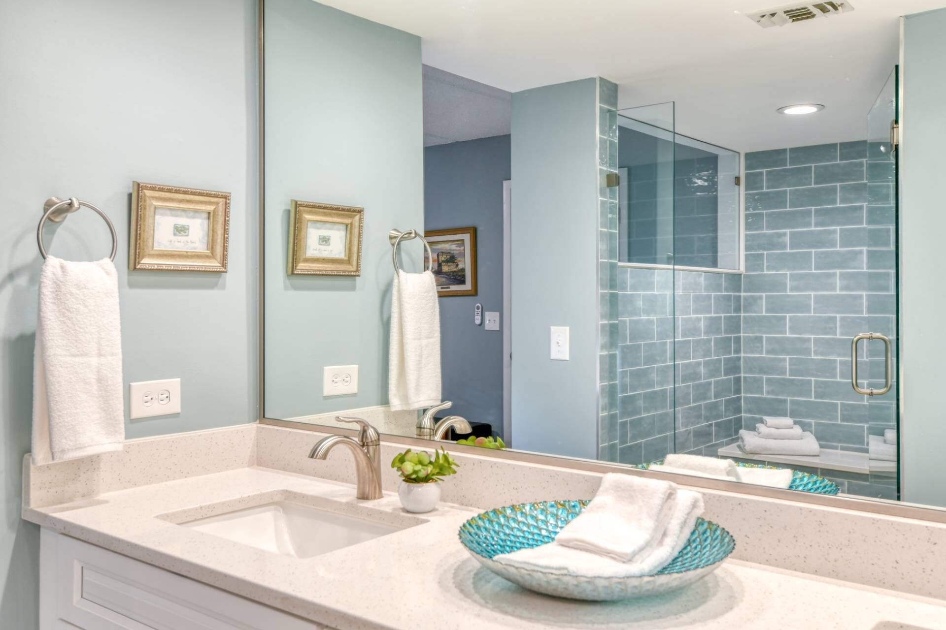 A modern bathroom with a sink, mirror, and glass shower enclosure.