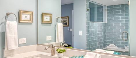 A modern bathroom with a sink, mirror, and glass shower enclosure.