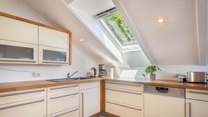Une cuisine moderne dotée d’une verrière, d’appareils électroménagers intégrés et d’un plan de travail en bois.