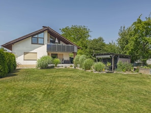 A two-story house with a balcony, a small garden, and a shed.